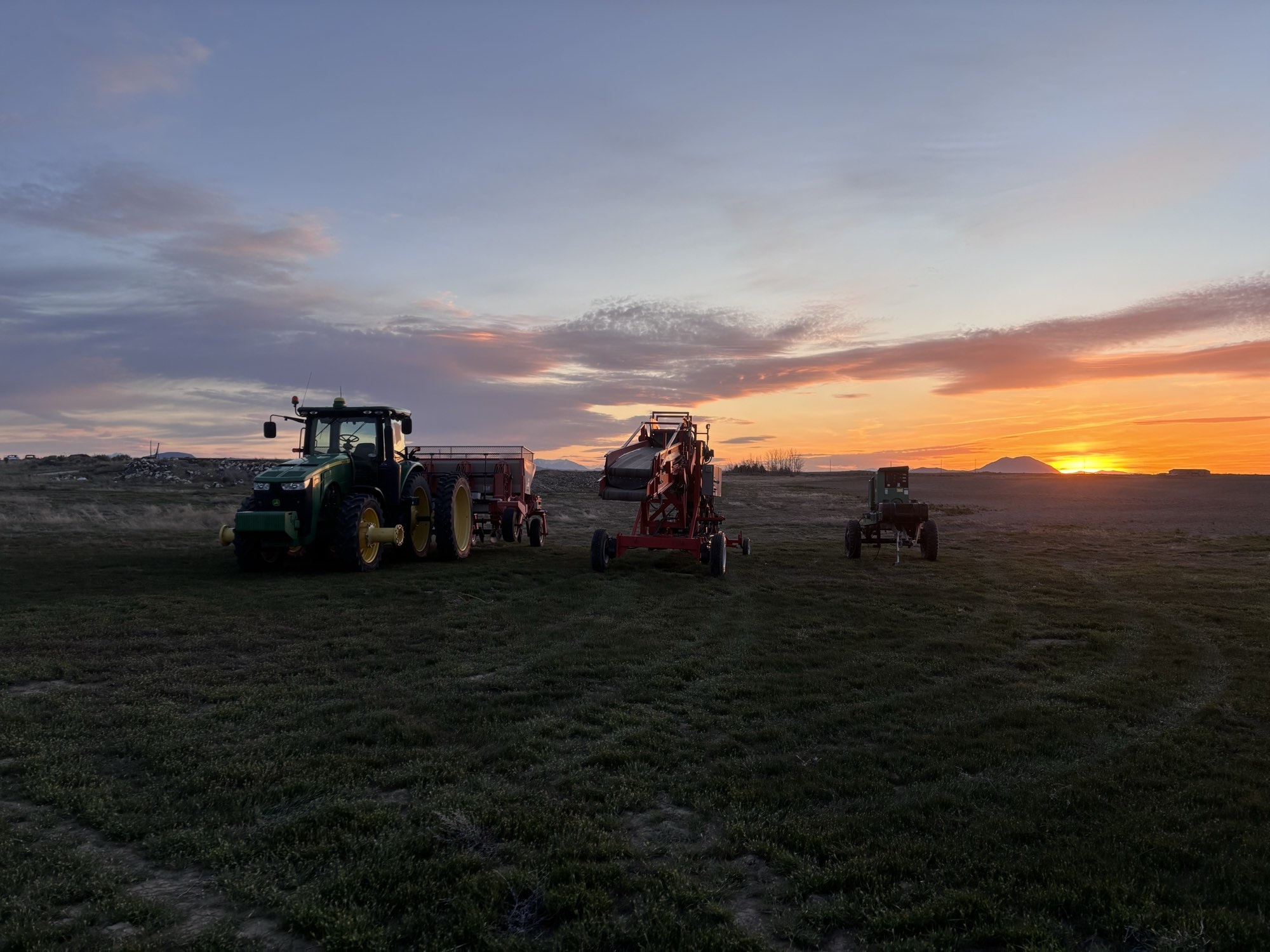 Benson Farms equipment lined up in a field at sunset