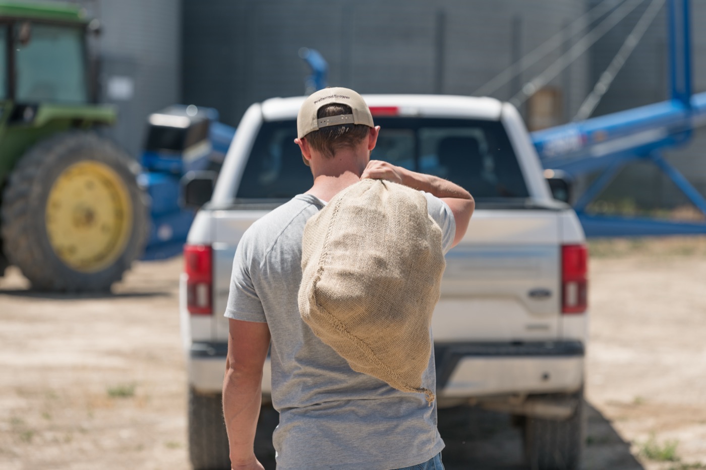 A Benson Farms worker carrying a burlap sack of potatoes past a pickup truck